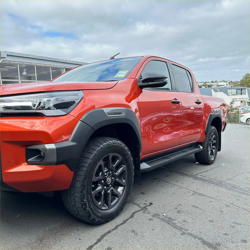 Vibrant red toyota hilux 2021-2024 sr5 cruiser with grey oem style fender flares and rugged off-road tires