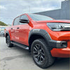 Vibrant orange toyota hilux 2021-2024 sr5 cruiser with black accents and grey oem style fender flares, rugged off-road tires