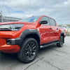 Vibrant red toyota hilux 2021-2024 sr5 cruiser with grey oem style fender flares and rugged off-road tires