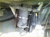 Black cylindrical metal fuel filter with dzus quick release clamp and attached hoses under land rover vehicle