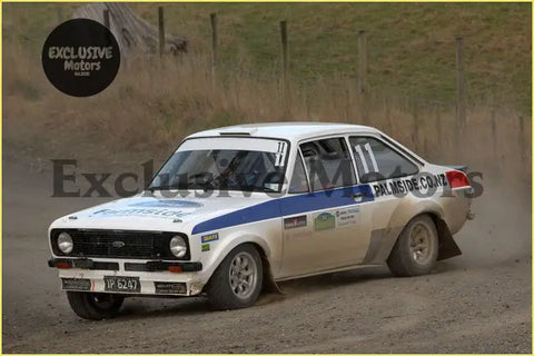 White and blue ford escort mk2 rally car with dirt splattered body and racing number 11 featuring alloy front spoiler