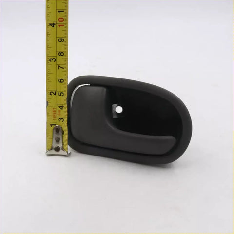 Gray lh door handle for Mazda B-Series made of black plastic with curved design and mounting hole shown from back side