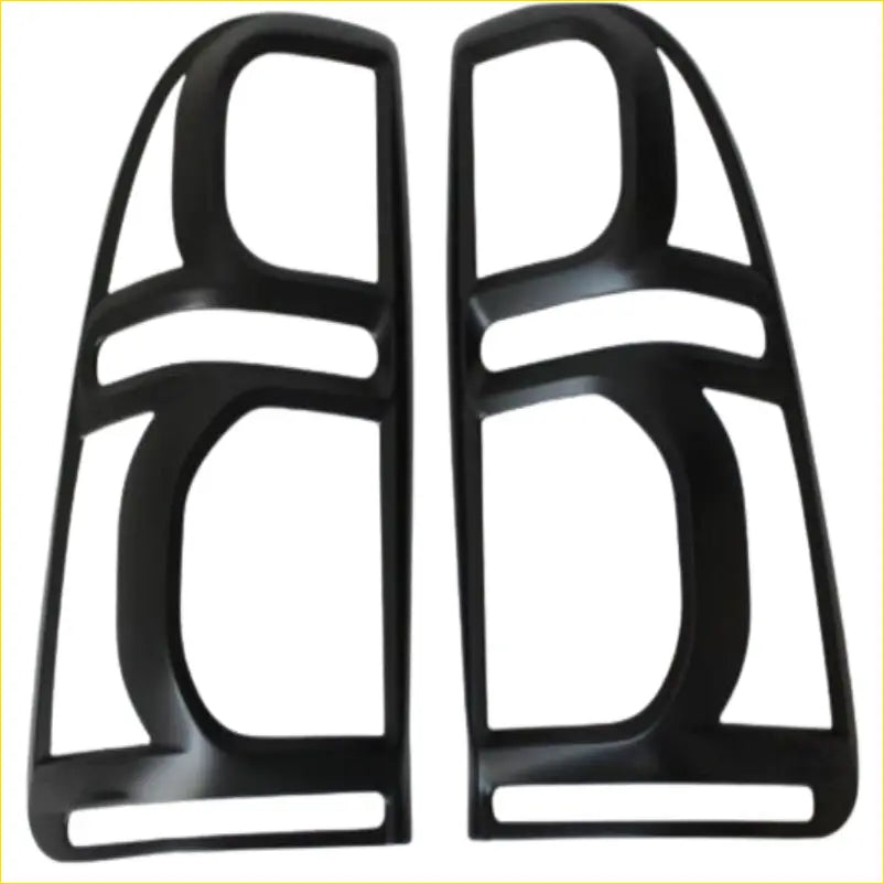 Black plastic headlight trim guards with glossy finish and angular cutouts for Toyota Hilux 2012-2015 headlights