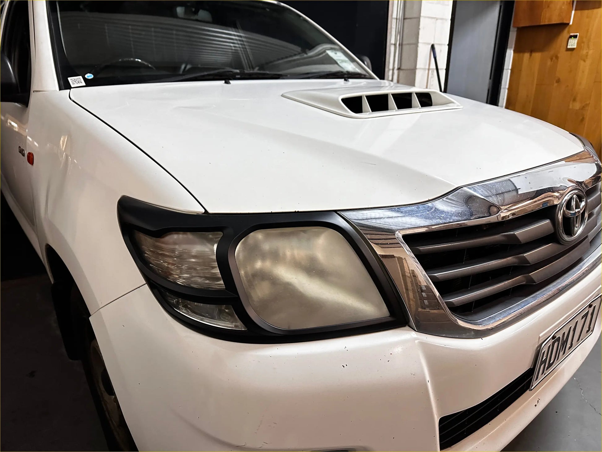 White toyota hilux 2012-2015 with chrome grille and black headlight trim featuring headlight and taillight covers
