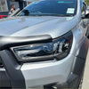 Silver metallic Toyota Hilux 2021-2024 SR SR5 with black plastic headlight covers and front bumper trim