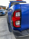 The back side of a vibrant blue ford ranger with bold red matte taillight covers and 4x4 badge visible