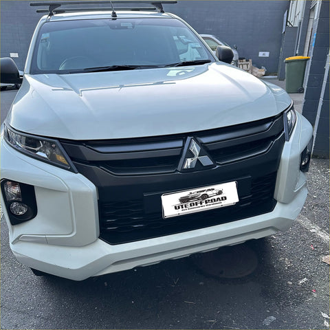 White mitsubishi triton 2019-2023 with matte black headlight covers black grille and roof rack utility vehicle