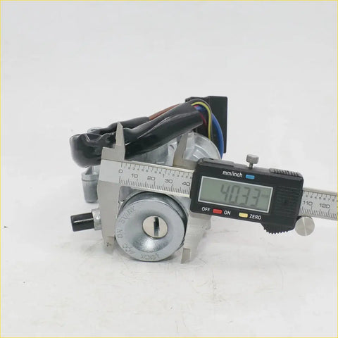 Silver metal ignition door fuel cap lock with keyhole and black wiring mounted on digital caliper for toyota hilux models
