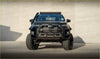 Black toyota pickup truck with rugged off-road tires kenda klever mt2 33x12.5 r20 and roof-mounted light bar