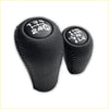 Black leather wrapped gear shift knobs with white embroidered gear patterns for a leather gear knob kit