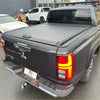 Rear view of black textured manual roller shutter tonneau cover with handle on mitsubishi triton 2024+ pickup truck