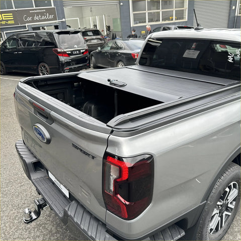 Gray metallic manual roller shutter bed cover made of metal on ford ranger sport pickup truck back side