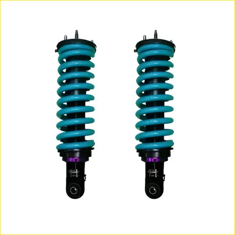 A pair of vibrant teal coil-over suspension shocks with black mounts and purple accents for mitsubishi pajero 2000 on swb
