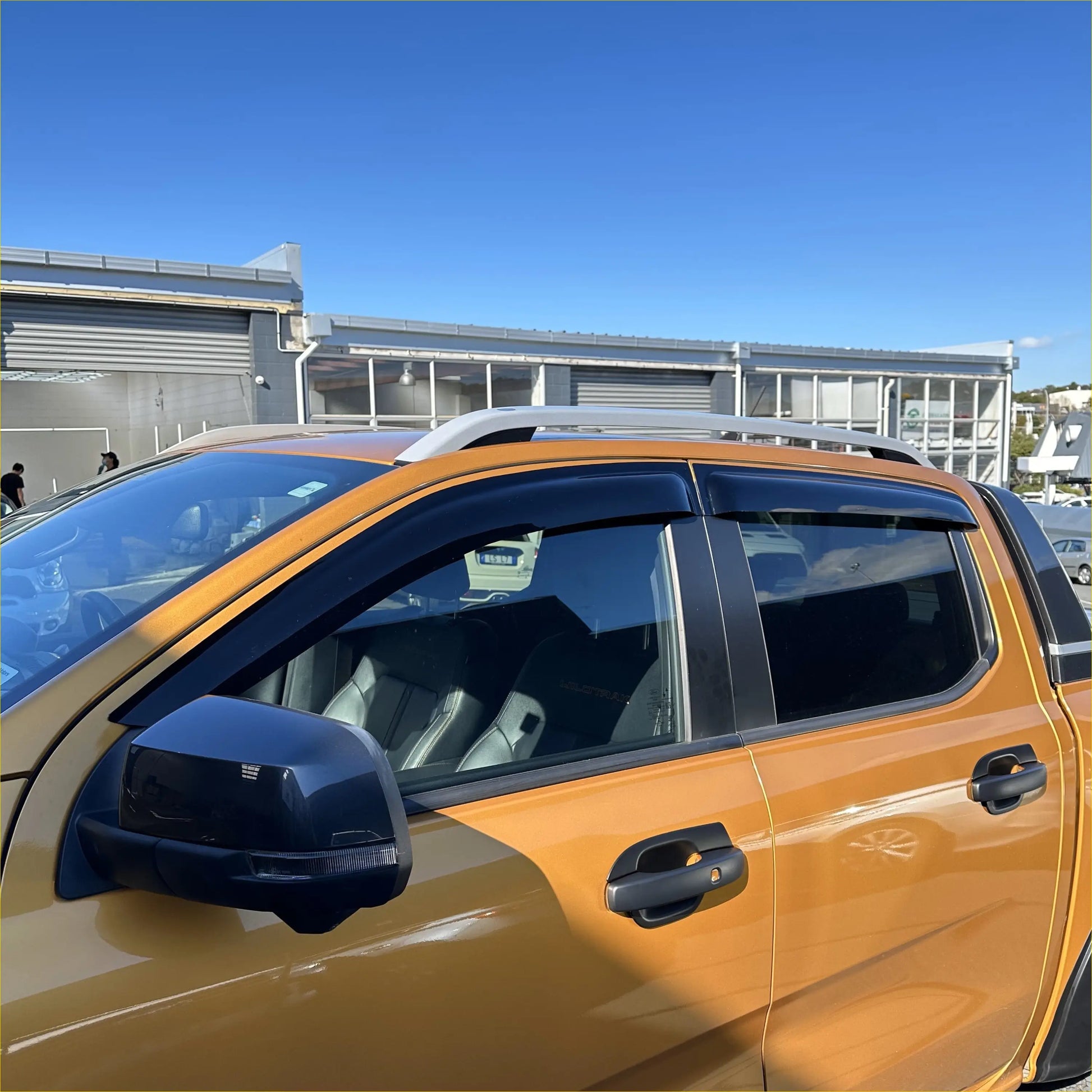 Black plastic window visors installed on the orange ford ranger 2022+ with monsoon and bonnet guard kit