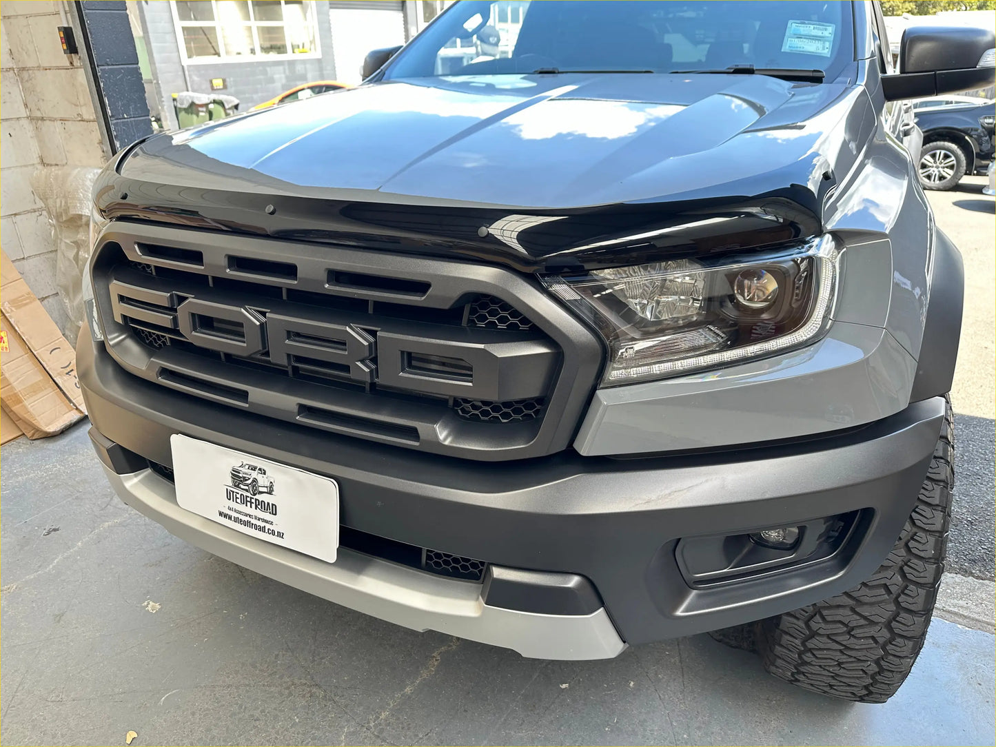 Gray metallic ford ranger raptor with black front grille and rugged tires featuring monsoon bonnet guard oem style px2 px3 2016-2021
