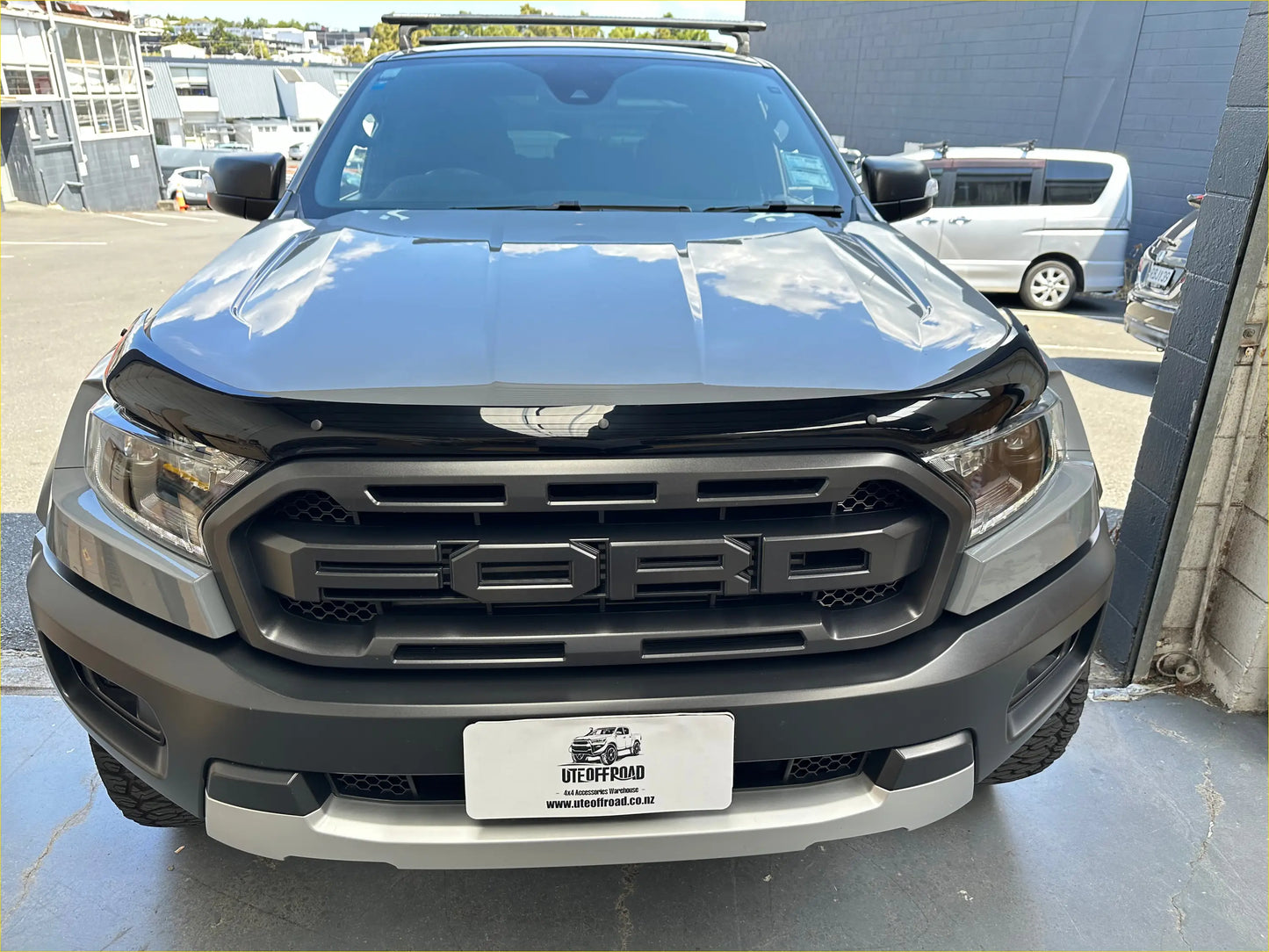 Black and silver ford ranger wildtrak with bold grille rugged tires and roof rack featuring monsoon and bonnet guard