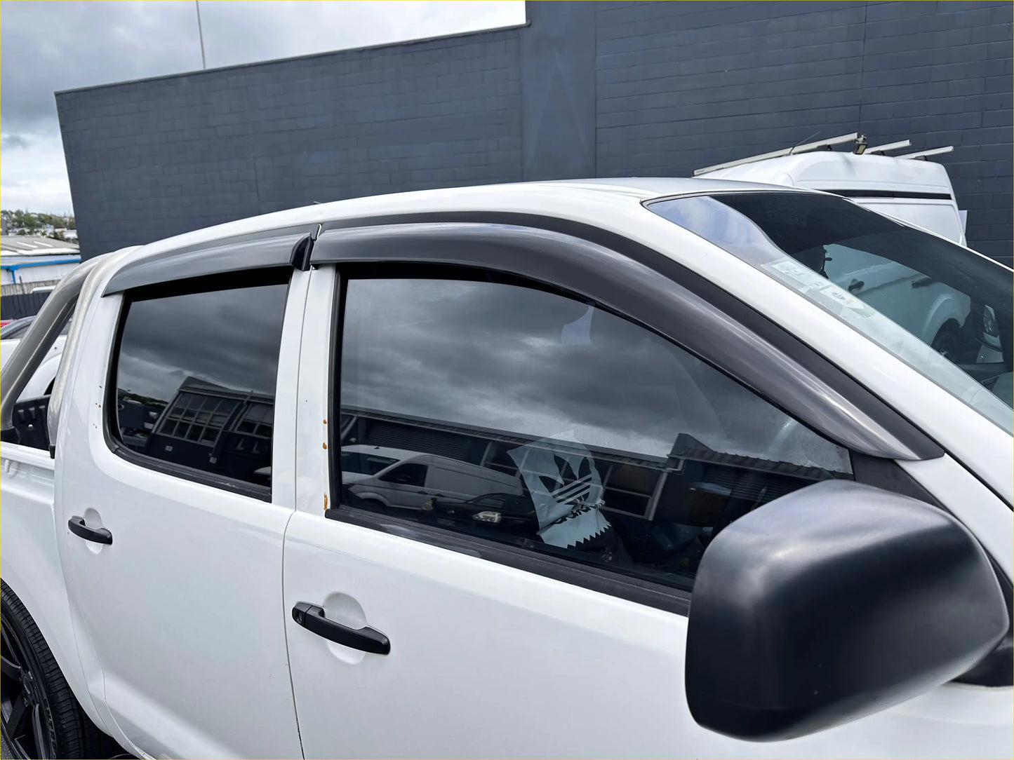 Black plastic window visors installed on a white toyota hilux 2005-2012 with monsoon and bonnet guard