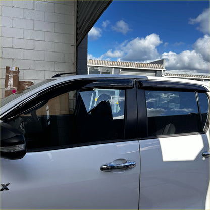 Black plastic window visors installed on a white toyota hilux 2015-2020 with monsoon and bonnet guard