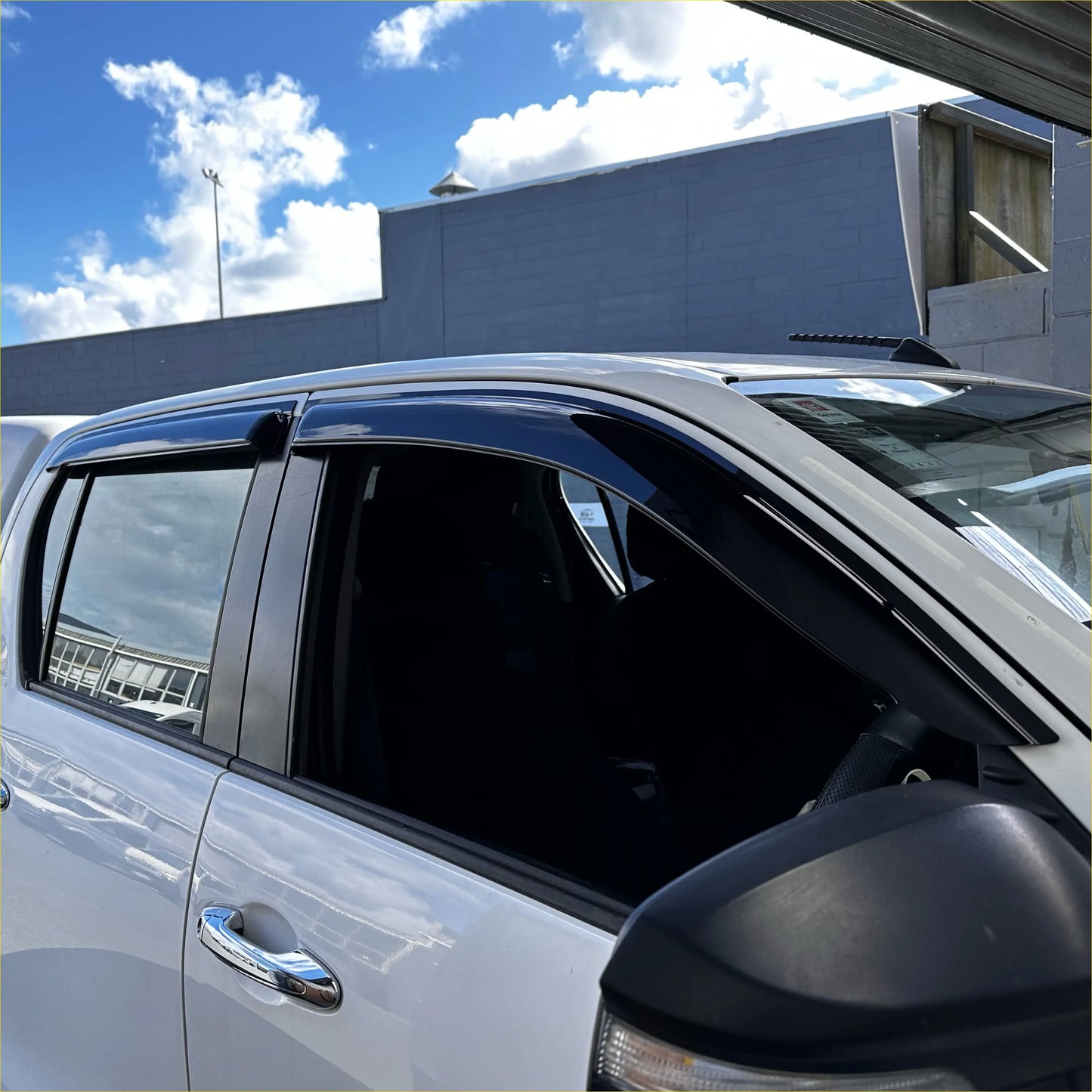Black plastic window visors installed on a white toyota hilux pickup from monsoon and bonnet guard 2015-2020