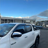 White toyota hilux pickup with black side mirrors and chrome accents featuring monsoon and bonnet guard 2021-2025
