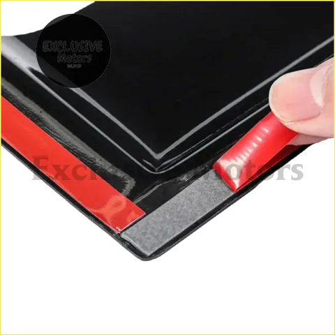 Black glossy adhesive strip with red backing being peeled off the back of monsoons window weather shield for toyota hilux