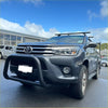 Dark gray toyota hilux with a matte nudge bar compatible with front sensors black bull bar and roof rack visible