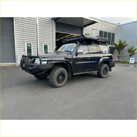 Black nissan patrol gu1 and gu4 with rockarmor brushbar, rugged offroad tires, and roof rack for 4wd adventures