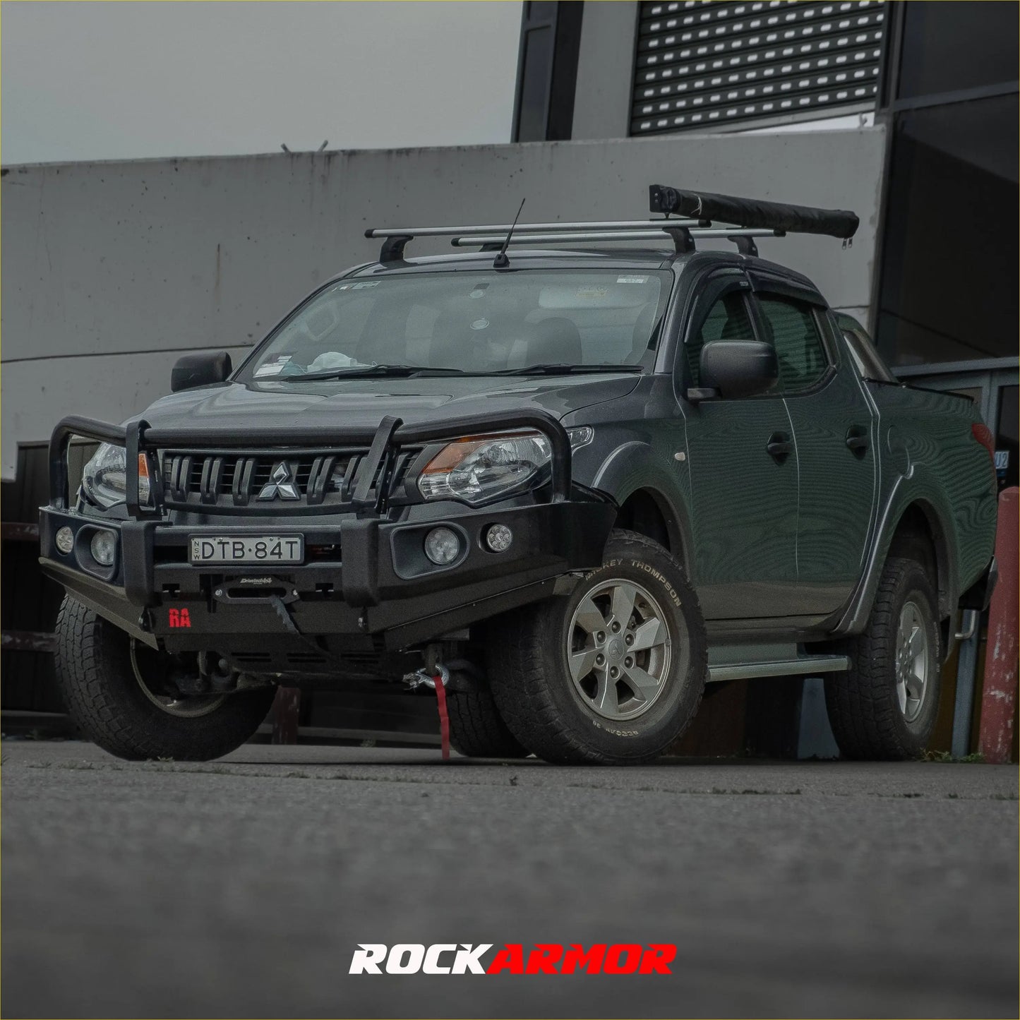 Dark green mitsubishi triton mq with a black steel rockarmor elite bullbar front bumper and roof rack