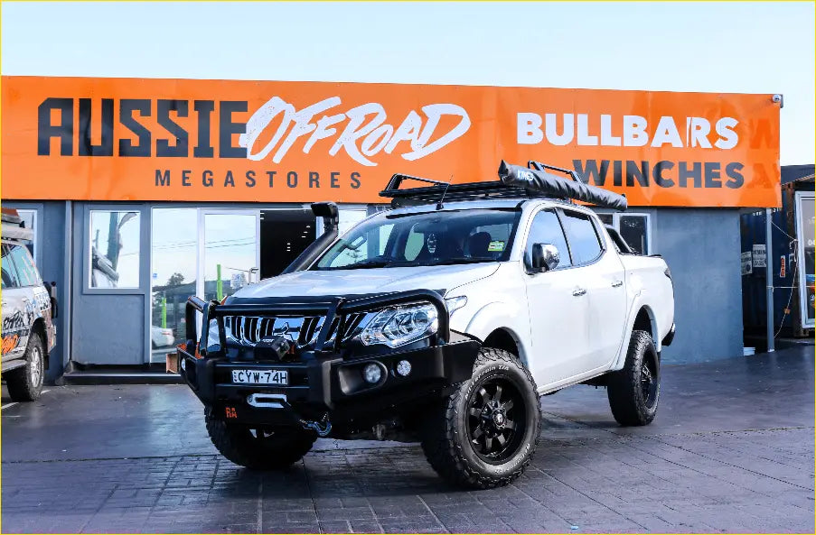 White mitsubishi triton with black roof rack featuring rockarmor elite steel bullbar for off-road protection