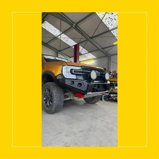 Black rugged steel rockarmor gt hoopless bullbar with circular led lights and red tow hook on gold ford ranger