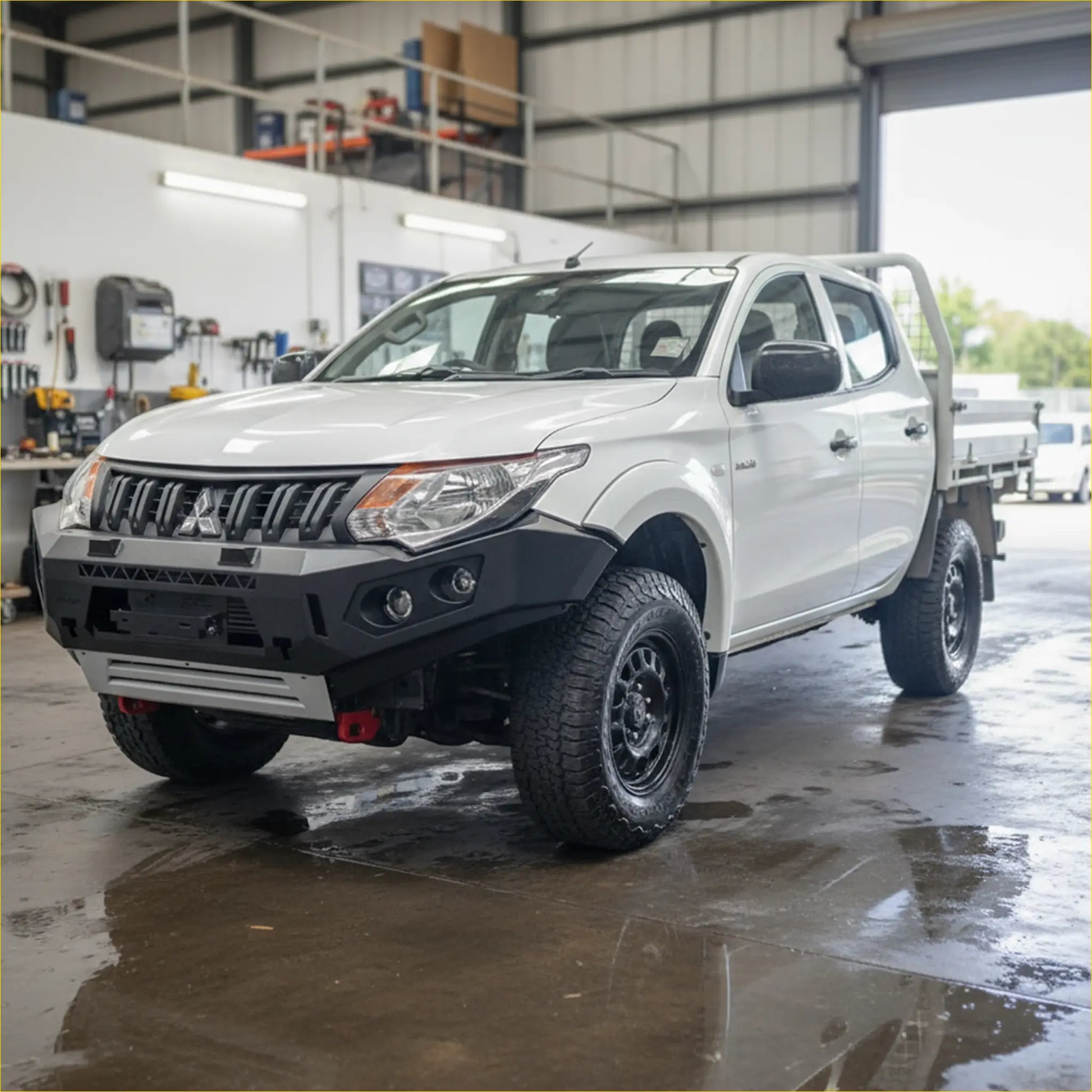 White mitsubishi triton with black off-road tires featuring rockarmor gt steel hoopless bullbar rugged front bumper