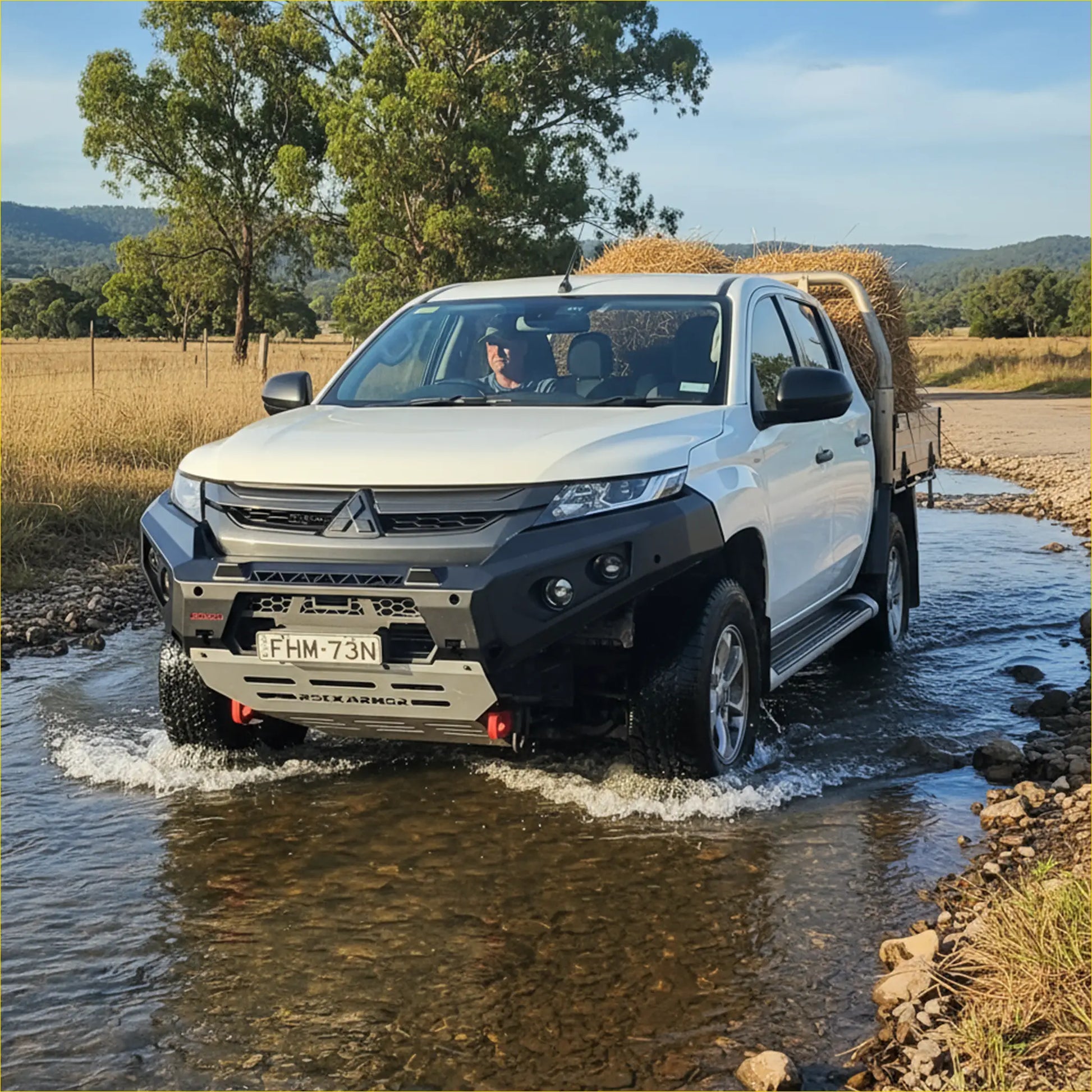 White mitsubishi triton with black rockarmor gt steel hoopless bullbar carrying hay in the bed