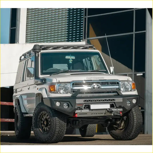 Silver toyota land cruiser 70 with black off-road tires and rugged rockarmor gt steel hoopless bullbar front bumper
