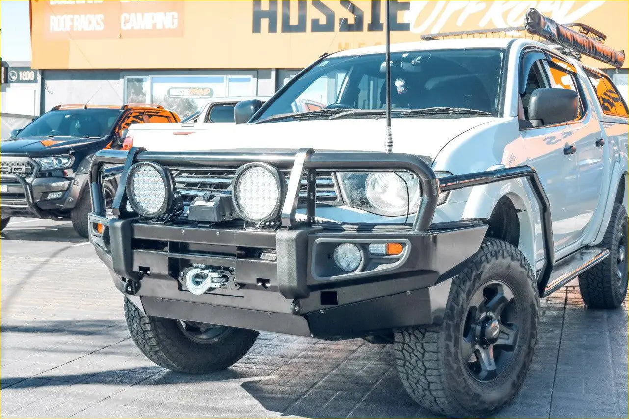 Silver Mitsubishi Triton pickup with black Rockarmor premium bullbar combo pack and off-road tires for rugged use