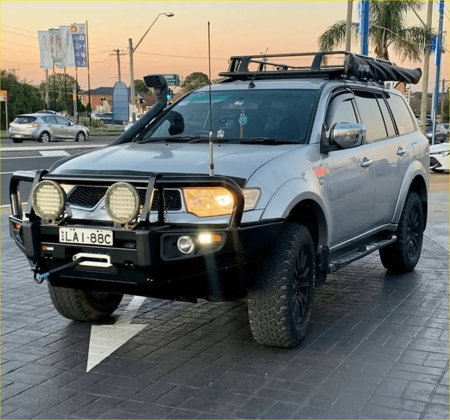 Silver mitsubishi pajero sport suv with black steel rockarmor premium bullbar and roof rack for off-road use