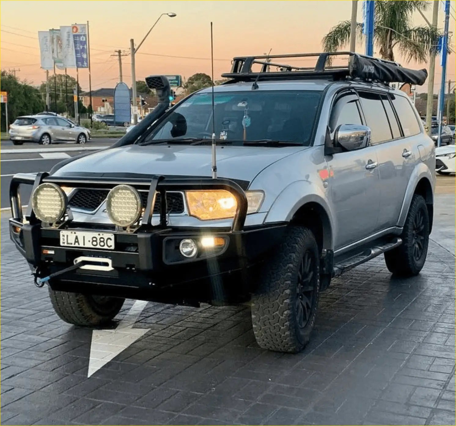 Silver mitsubishi pajero sport suv with black steel rockarmor premium bullbar and roof rack for off-road use