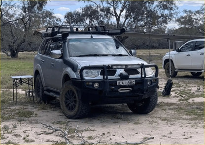 Silver mitsubishi pajero sport with rockarmor premium steel bullbar black off-road tires roof rack and bumper guard