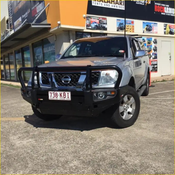 Silver nissan navara d40 pickup with rockarmor premium steel bullbar featuring black front bumper guard and chrome accents
