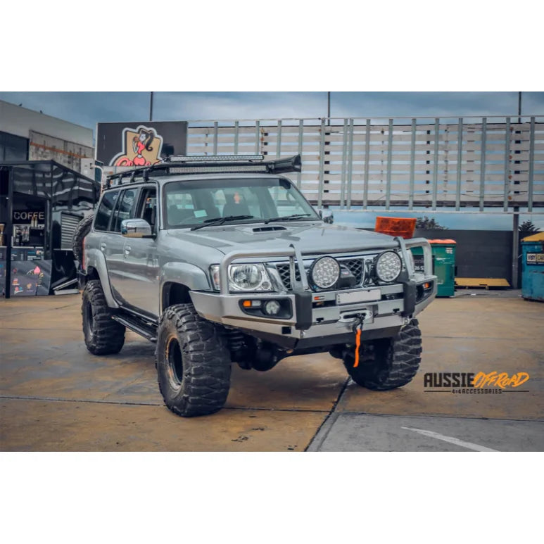 Silver off-road vehicle with oversized tires showcasing Rockarmor premium steel bull bar