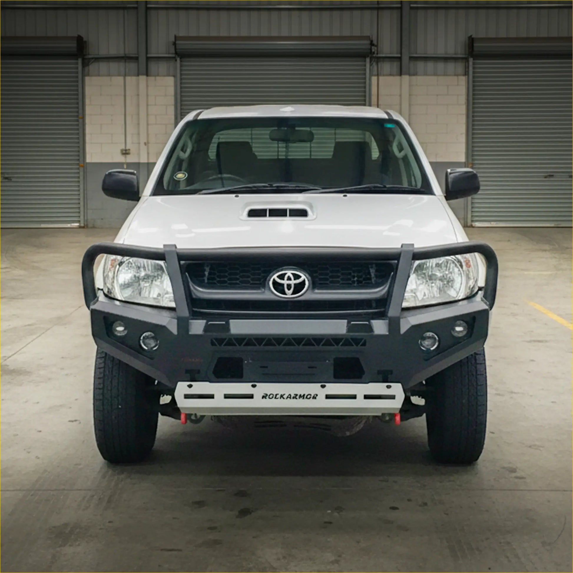 White toyota hilux n70 2005-2011 with a black rokarmor premium steel bullbar front bumper guard and grille