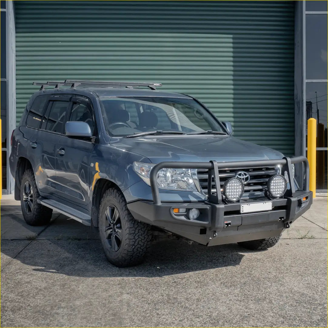 Dark gray toyota land cruiser with black off-road tires and rockarmor premium steel bullbar featuring led lights