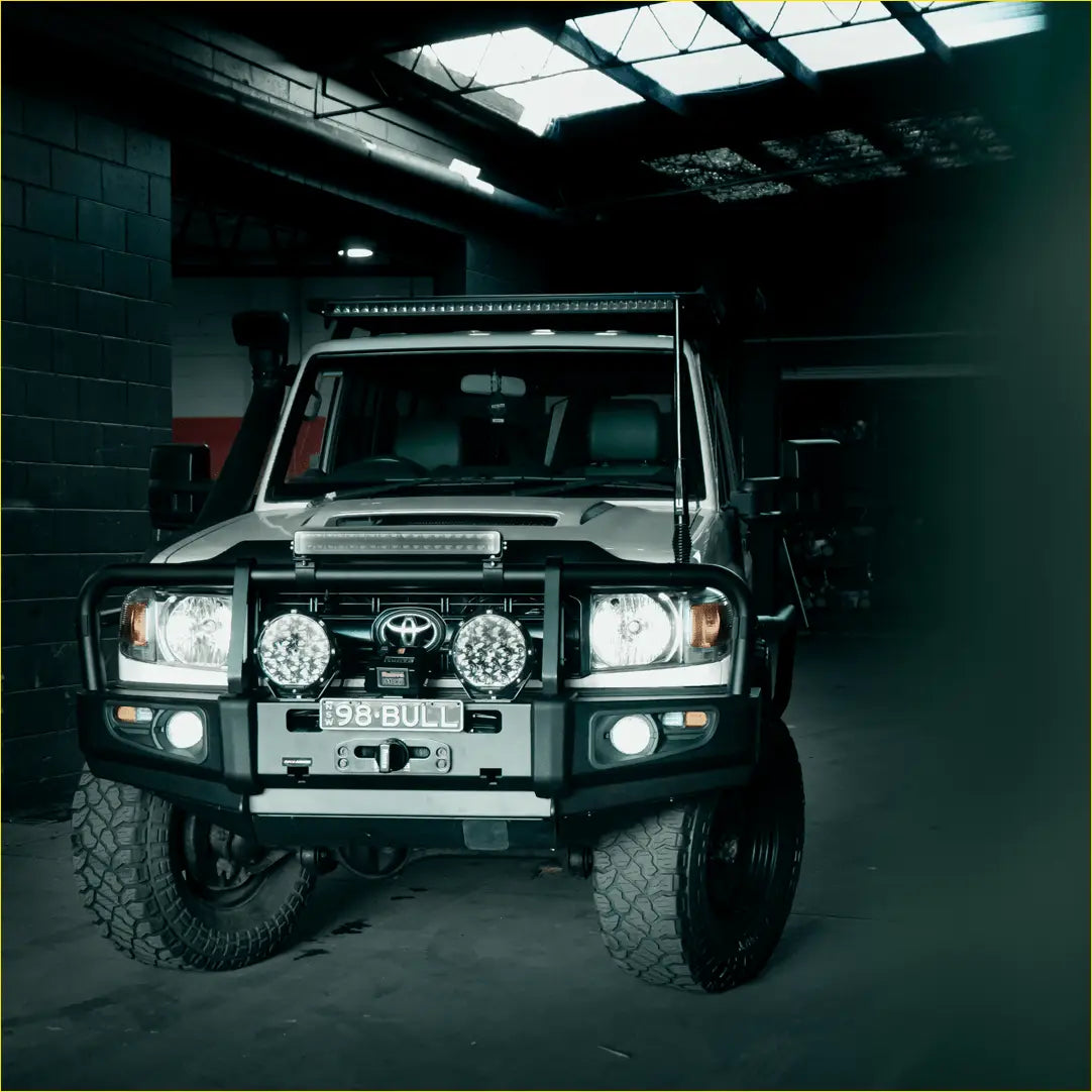 Silver toyota land cruiser with black rockarmor premium steel bullbar and rugged off-road tires front view