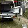 White rock armor foldable camping stove with black burner and knobs mounted on the rear of prado 120 vehicle