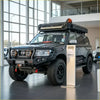 Black nissan patrol gu4 with rockarmor rock pack featuring gt hoop bullbar rock sliders rugged tires and roof rack gear