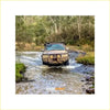 Brown rugged toyota landcruiser fj105 with premium rockarmor bullbar and rock sliders driving through shallow water