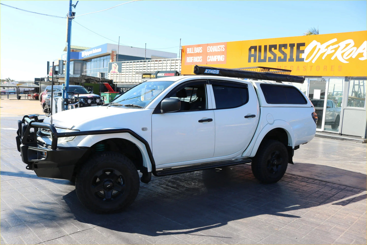 White mitsubishi triton with black rockarmor steel rockslider side steps roof rack and protective guard visible from side