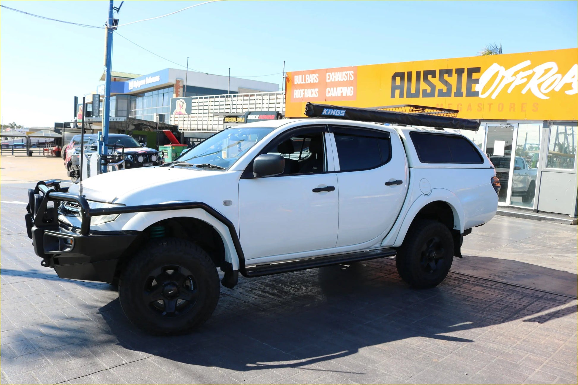 White mitsubishi triton with black rockarmor steel rockslider side steps roof rack and protective guard visible from side