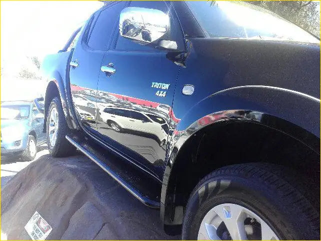 Black Mitsubishi Triton 4x4 pickup showing Rockarmor steel rockslider side steps with chrome accents from the side