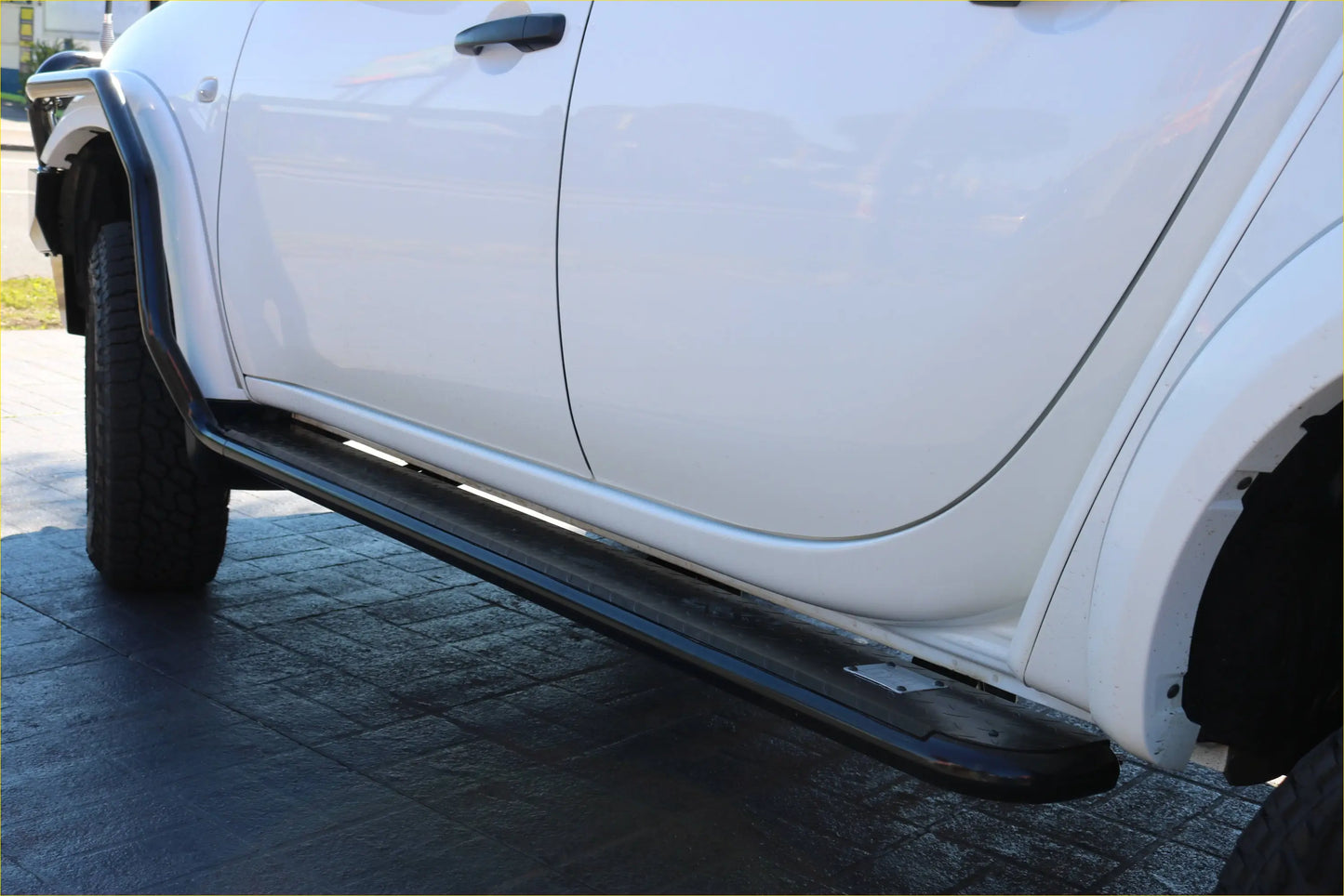 Black matte steel rockarmor rockslider side step mounted on white mitsubishi triton ml mn door showing back side