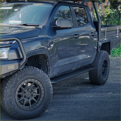Black matte pickup truck with rockarmor steel rockslider side steps featuring rugged off-road tires and reinforced bumper
